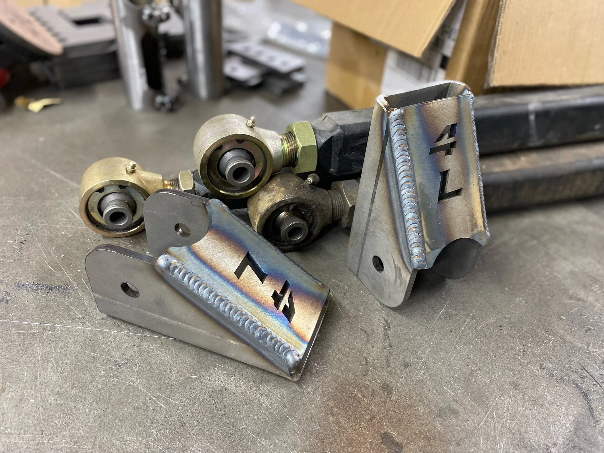 Welded 4Link4WD lower control arm brackets with control arms in background.